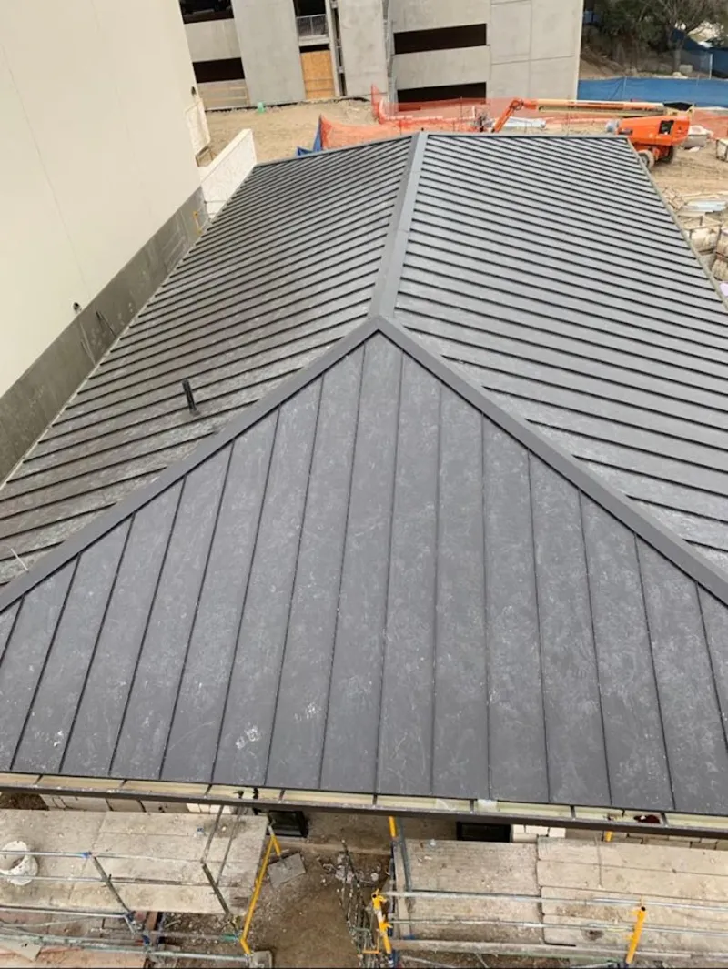 Commercial metal roof construction with crane equipment in Broomfield